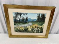 Front view of the framed painting showing the scene with lupins, road, trees, and mountains.
