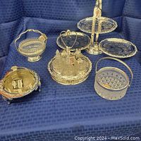 Full set of Queen Anne vintage silver plated serverware pieces displayed on blue cloth, showing variety and overall condition.