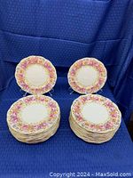 Two stacks of Royal Albert dinner plates with the Serena floral pattern featuring pink and yellow roses with gold detailing.