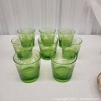Front view of 8 fern green glasses arranged in rows, showing etched fern leaf pattern in translucent green glass.