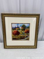 Framed landscape print with detailed view of the colorful scene and ornate gold frame.