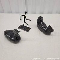 Three sculptures on table: two soapstone birds and one abstract metal figure