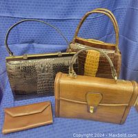 Three vintage handbags and one wallet arranged on a blue textured cloth background.