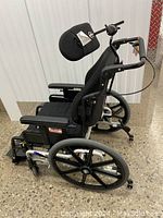 Side view of manual wheelchair showing padded backrest, headrest, rear wheel and frame