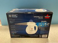 Box of Bissell Steamshot Deluxe handheld steam cleaner showing front graphics and product image.