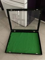 Open view of wooden display case showing green felt interior and plexiglass lid with hinges and metal hardware.