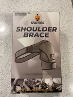 Box showing Sparthos Shoulder Brace branding and information that it is interchangeable for both shoulders.
