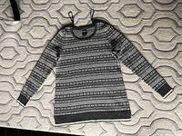 Front view of grey patterned Far West sweater laid flat on a textured grey surface.
