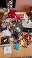 Full view of varied Christmas ornaments including poinsettias, a boxed holographic crystal angel, and assorted items spread on a wooden table