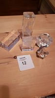 Top-down view of all 5 glass sculptures on wooden table with sales card