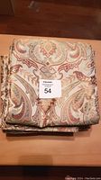 Folded brocade drapery panels stacked with visible decorative pattern