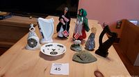 View of all Irish souvenir items including dolls, harp figurines, marble piece, bell, and decorative plate on a wooden surface