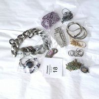 Overall photo of all 11 jewelry items arranged on a white cloth, showing variety of chains, beads, bracelets, pendants, and earrings.