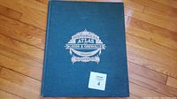 Blue cloth upholstered atlas cover showing the title 'Historical Atlas of Leeds & Grenville Ontario Illustrated' with white ornate lettering and decorative graphic.