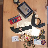 Lot overview showing decanter, belt, patches, brass buttons, letter, and small badge.