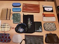 Overview photo showing all assorted ladies' pocketbooks, wallets, and change purses on a wooden table.