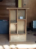 Front view of rustic barnboard wall cabinet showing multiple open compartments and small drawer with white knob.
