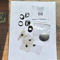 Full lot overview showing rings, brooch, charms, and pendant on a paper background