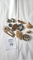 Full overview of 10 vintage brooches with varying designs and materials, including enamel, faceted stones, rhinestones, and metalwork.