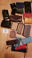 Overview of 19 assorted ladies' wallets, change purses, and pouches laid out on a surface showing various colors, sizes, and materials.