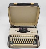 Open view of 1966 Olympia SF De Luxe typewriter inside original beige travel case showing keys and mechanism.