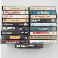 Top view of stacked cassette tapes showing spine titles of artists such as Led Zeppelin, Buddy Holly, Michael Jackson, Rolling Stones.