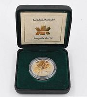 Daffodil coin displayed inside green velvet-lined presentation box with inner lid branding