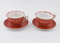 Front angle view of two vintage Japanese porcelain tea cups and their matching saucers, showing detailed floral pattern and gold accents.