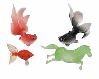 Four glass and porcelain figurines: three koi fish in orange, black and orange glass, and a jade green glass horse.