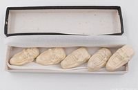 Five distinct porcelain chopstick holders displayed in original box, showing shape as traditional Japanese mask faces and creamy color.