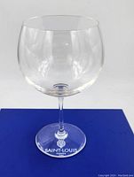 Clear round wine/brandy glass with long stem, viewed frontally, showing smooth edges and clear crystal bowl on blue branded box.