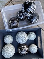 Photo of all ceramic balls showing a mix of black and beige ceramic balls with intricate white and gray-blue patterns in plastic and cardboard containers.