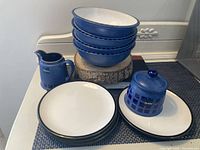 Overview of bowls stacked, plates spread, cream pitcher, and sugar bowl with lid displaying the full lot