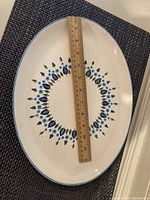 Top view of oval platter showing mid-century blue and cream floral pattern and ruler for scale approximately 13 inches long.