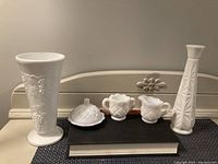 Full set of milk glass miniatures on a table including covered sugar bowl, creamer, two vases