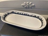 Full view of the white oblong serving platter showing the black New York City skyline along the rim, labeled with landmark names.