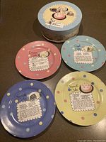 Set of four Rosanna brand dessert plates with different polka dot border colors (pink, blue, yellow, green). Each plate has a printed dessert cake recipe and small cake illustration in the center.