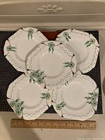Set of 4 shamrock-themed luncheon or dessert plates, square shaped with scalloped edges, arranged with a ruler showing size.