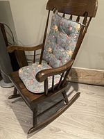 Full view of the solid wood rocking chair with blue floral cushions attached to seat and backrest.