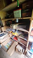 Wide view of wooden shelves filled with cardboard and wooden boxes, papers, and assorted items.