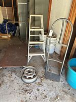 Full view of the lot including the white aluminum ladder, flatbed roller, and hand truck showing condition and dirt accumulation.