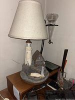 Full lamp with beige fabric conical shade, lighthouse model, boathouse, and 'Santa Cruz' signage on wooden dock base.