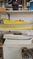 Yellow 'Miss Patti Kai-I' catamaran on top shelf and white hull beneath