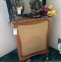 Front view of one vintage wooden cabinet speaker with fabric grill and decorative wood trim, surrounded by floral decoration on top and green carpet below.