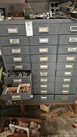 Full view of gray metal tool storage cabinet with multiple labeled drawers, some open showing contents