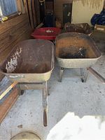 Four wheelbarrows in a shed, showing rust and wear on metal surfaces