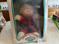 Front view of the 1984 Cabbage Patch Kids doll in original box, showing jersey number 31 and birth certificate behind.