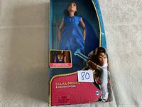 Front view of Diana Princess doll in blue dress inside original packaging. Box shows wear and tattering on bottom corner.