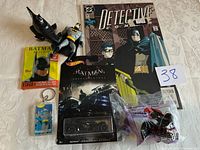 Photo showing the full collection of Batman items including figures, comic book, Hot Wheels car, trading cards, and keychain.