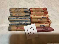 Photo showing 12 rolled coin sets arranged on a table, labels visible indicating years for nickels and pennies.
